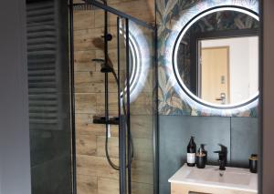 a bathroom with a shower and a sink and a mirror at Luxus Apartament Bella in Gdynia