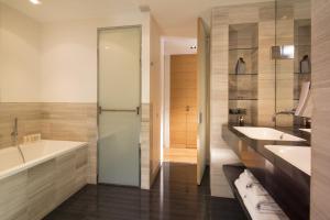 a bathroom with two sinks and a tub and a shower at Hotel Marignan Champs-Elys&eacute;es in Paris