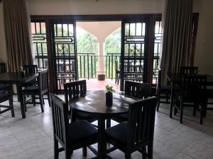 a dining room with tables and chairs and a balcony at The Fortuna Apartment in Kabale