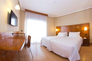 a bedroom with a large white bed and a desk and a table at NH San Pedro de Alcántara in Marbella