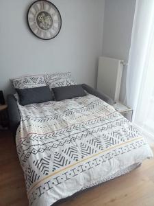 a bed in a bedroom with a clock on the wall at Bel appartement proche gare et centre-ville in Rambouillet
