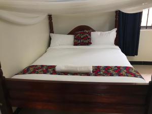 Una cama con sábanas blancas y almohadas. en The Fortuna Apartment en Kabale
