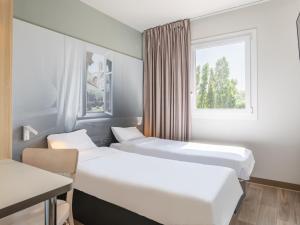 twee bedden in een kamer met een raam bij B&B HOTEL Aix en Provence Venelles in Venelles