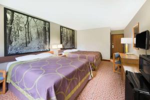 a hotel room with two beds and a flat screen tv at Super 8 by Wyndham Pella in Pella