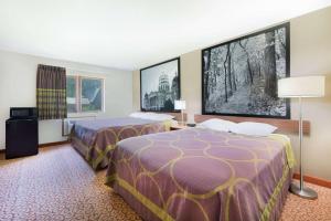 een hotelkamer met 2 bedden en 2 ramen bij Super 8 by Wyndham Pella in Pella