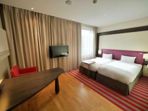 a hotel room with a large bed and a red chair at Mercure Warszawa Grand in Warsaw