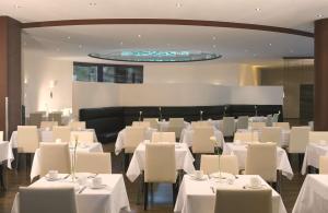 NH Dresden Neustadt في درسدن: غرفة طعام مع طاولات بيضاء وكراسي بيضاء