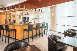 a bar in a restaurant with black chairs at NH Dresden Neustadt in Dresden