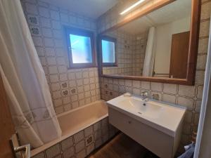 a bathroom with a sink and a tub and a mirror at Les Brinbelles 27 studio au pied des pistes in Les Deux Alpes