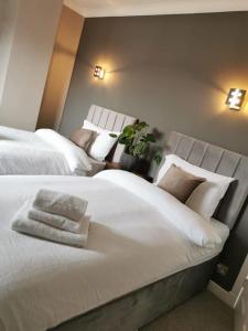 1 dormitorio con 2 camas con sábanas y almohadas blancas en Limekilns House, en Clydebank