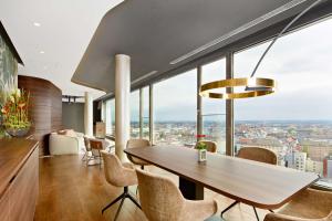 a dining room with a table and chairs and large windows at NH Collection München Bavaria in Munich