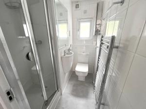 biała łazienka z toaletą i prysznicem w obiekcie Beautifully refurbished 5-bed - Great Transport - Free Parking (sleeps 12) w Londynie