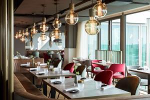 un restaurant avec des tables, des chaises et des lumières dans l'établissement NH Collection Eindhoven Centre, à Eindhoven