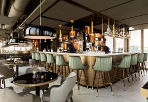 a restaurant with a bar with chairs and tables at NH Collection Eindhoven Centre in Eindhoven