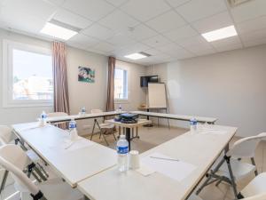 uma sala de aula com mesas e cadeiras e garrafas de água em B&B HOTEL Aix en Provence Venelles em Venelles
