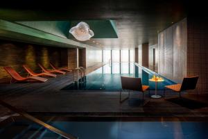- une piscine avec des chaises et une table dans un bâtiment dans l'établissement Anantara The Marker Dublin- A Leading Hotel of the World, à Dublin