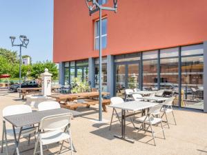 een groep tafels en stoelen voor een gebouw bij B&B HOTEL Aix en Provence Venelles in Venelles