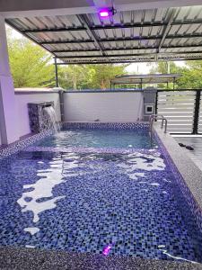 una piscina con suelo de baldosa azul y una cascada en Homestay MdmMai Private Pool, en Masjid Tanah