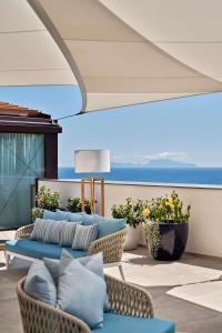 eine Terrasse mit einem Sofa, Stühlen und Meerblick in der Unterkunft The Britannique Hotel Naples, Curio Collection By Hilton in Neapel