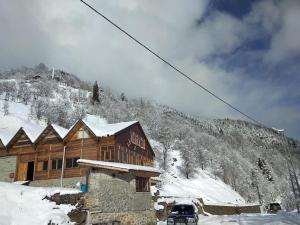 een blokhut in de sneeuw naast een berg bij Meydan Şimşir Bungalov in Çamlıhemşin