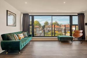 a living room with a green couch and a large window at Modern Penthouse in Wembley in London