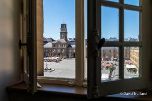 a window view of a city with a clock tower at Suite Mana - Maui - Place Ducale in Charleville-Mézières