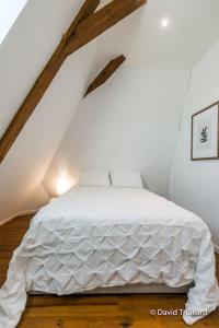 sypialnia z białym łóżkiem na poddaszu w obiekcie Suite Mana - Maui - Place Ducale w mieście Charleville-Mézières
