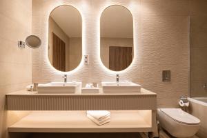 ein Badezimmer mit zwei Waschbecken, einem Spiegel und einem WC in der Unterkunft Hotel Gerardus in Szeged