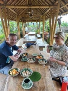 a man and a woman sitting at a table with food at BaliFarmhouse in Banjarangkan