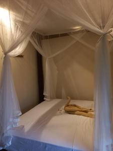a white canopy bed with white curtains on it at BaliFarmhouse in Banjarangkan
