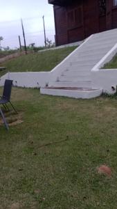 a chair sitting in the grass next to some stairs at Biju's Little Farm in Ibiúna