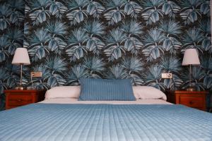a bedroom with a blue bed and a wall with plants at Hotel Isla Menor in Dos Hermanas