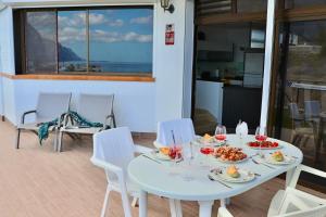 un tavolo bianco con cibo e bevande su un balcone di Panoramic Seaview Escape a Puerto de Santiago