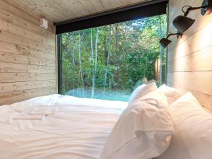 Cama en habitación con ventana grande en Chic Sauna Cabin Near the Sea - VULIN Cabin Nº01, 