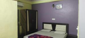 a bedroom with a bed with a purple wall at Mostel hotel in Jaipur