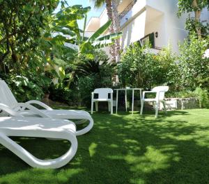 a group of white chairs and tables in a yard at Hotel Villa Angelica in Ischia
