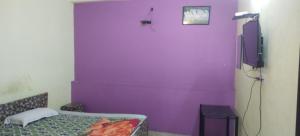 a purple room with a bed and a tv at Mostel hotel in Jaipur
