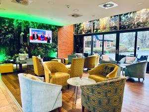 a lobby with chairs and tables and a wall of windows at Woodland Grange in Leamington Spa