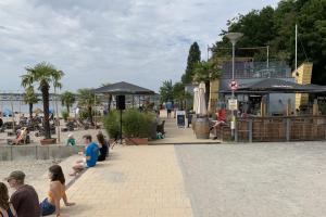 eine Gruppe von Menschen, die auf einem Bürgersteig in Strandnähe sitzen in der Unterkunft Zentrale und komfortable "Küsten-Residenz" in Neustadt in Holstein