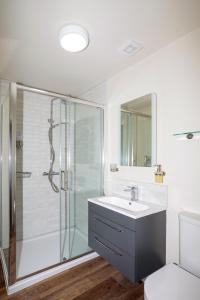 a white bathroom with a shower and a sink at 30 Chipping Norton - Luxury Holiday Apartments in Chipping Norton