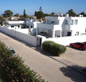 Un bâtiment blanc avec une voiture garée devant. dans l'établissement Villa Horacia, à Sanlúcar de Barrameda