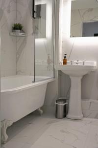 ein weißes Badezimmer mit einer Badewanne und einem Waschbecken in der Unterkunft Gleneagles Luxury Apartment in Auchterarder