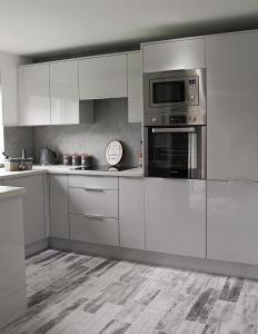 a kitchen with white cabinets and a microwave at Gleneagles Luxury Apartment in Auchterarder