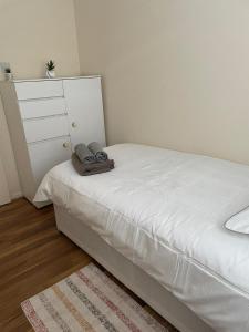 a small bedroom with a white bed and a dresser at Single and doubles rooms close to central London in London