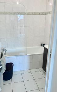 a white bathroom with a tub and a sink at Appartement 1 chambre proche Gare RER B Vert Galant - Parking et balcon privé - Proche Aéroport Roissy CDG - Parc Des Expositions - Paris - Stade de France - Astérix - Disneyland Paris in Villepinte