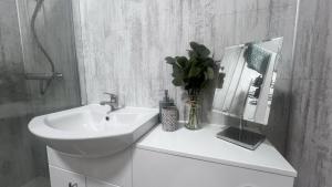ein weißes Badezimmer mit einem Waschbecken und einer Vase aus Blumen in der Unterkunft Beddoes Court Top Floor Studio with Sea Views in Saundersfoot