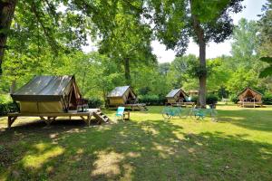 eine Gruppe von Cottages in einem Park mit Bäumen in der Unterkunft Camping Etang de la Vallée in Combreux
