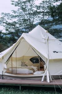 uma tenda branca com uma cama num campo em NatureLand Campsite em Shenzhen