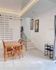a dining room with a table and chairs and stairs at Cheerful 27 Home with BBQ grill in Cheras