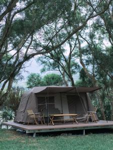 a tent with chairs and tables in a field at NatureLand Campsite in Shenzhen